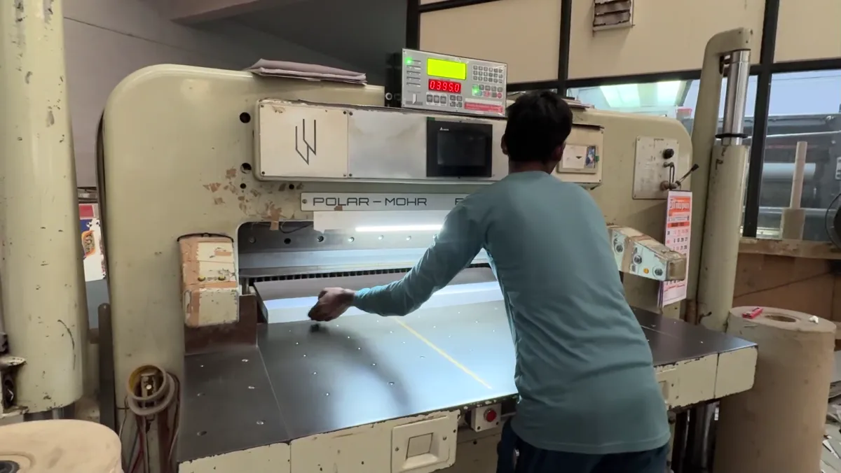 A team member positioning paper at the cutting machine